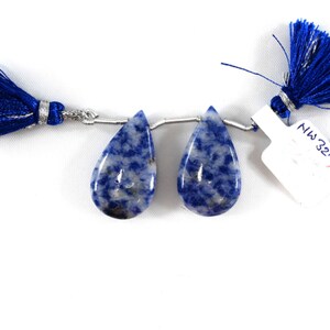 May include: Two teardrop-shaped blue and white gemstone beads with a silver connector. The beads are connected to a blue tassel on each end.