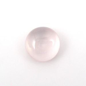 May include: A round, pale pink rose quartz cabochon gemstone.