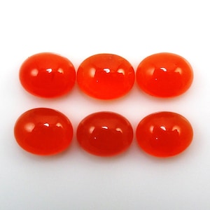 Könnte beinhalten: Sechs glatte, ovale geschliffene Karneol-Edelsteine in leuchtend orange. Die Steine sind in zwei Reihen zu je drei angeordnet.