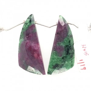 May include: Two green and pink gemstone cabochons with a triangular shape. The stones are connected by a silver wire.