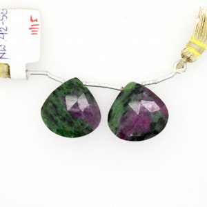 May include: Two green and pink gemstone beads with a faceted pear shape. The beads are strung on a silver chain with a tassel.