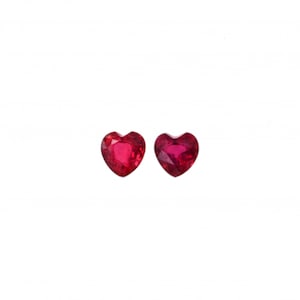 May include: Two heart-shaped ruby gemstones, each with a deep red colour and a faceted cut.