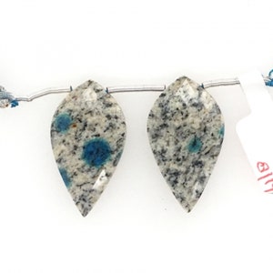 Può includere: Due perline di cianite blu e bianca a forma di pera infilate su un filo d'argento.