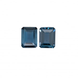 May include: Two blue topaz gemstones, cut in an emerald shape.