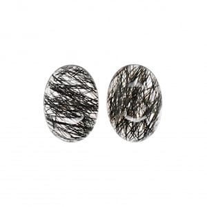 May include: A pair of oval-shaped earrings featuring clear quartz with black inclusions. The earrings are made from natural stone and have a distinctive, organic appearance.