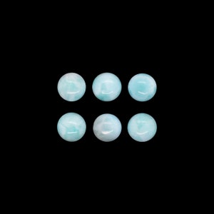 May include: Six round, light blue gemstone cabochons. The cabochons are smooth and polished.