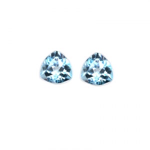 May include: Two light blue triangular gemstones with a faceted cut.