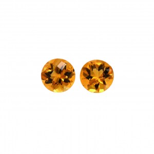 May include: Two round, orange citrine gemstones.