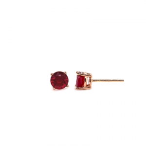 May include: A pair of gold stud earrings with a red gemstone in the centre of each earring.