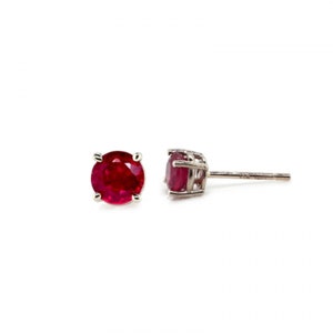 May include: A pair of ruby stud earrings with a silver setting. The earrings are round and have a classic design.