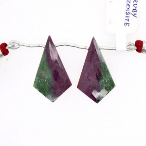 May include: Two green and pink gemstone pendants in a diamond shape. The pendants are strung on a silver chain.