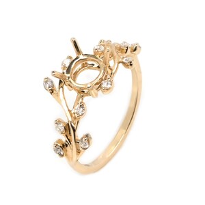 Puede incluir: Un anillo de oro con un delicado dise&ntilde;o de ramas engastado con peque&ntilde;os diamantes. El anillo tiene un engaste ovalado grande en el centro, perfecto para una piedra preciosa personalizada.