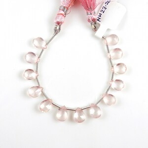 May include: A strand of pale pink rose quartz gemstone beads in a teardrop shape. The beads are strung on silver wire and are approximately 10mm in size. The beads are displayed on a white background.