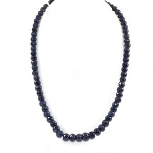 Puede incluir: Un collar de cuentas azul oscuro. El collar presenta cuentas redondas facetadas ensartadas. Las cuentas tienen un color profundo y saturado y una superficie reflectante. El collar se muestra sobre un fondo blanco.