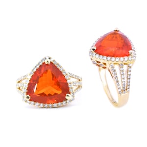 May include: A gold ring with a large, triangular, orange gemstone surrounded by a halo of smaller, white gemstones.