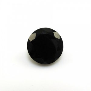 May include: A round, black gemstone with a faceted cut. The gemstone has a high polish and is set in a bezel setting.