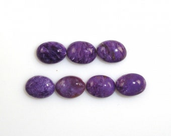 May include: Eight oval gemstones in shades of purple and violet are displayed on a white background. The polished stones have a glossy finish, with colour variations creating a marbled effect. The gemstones are arranged in two rows.