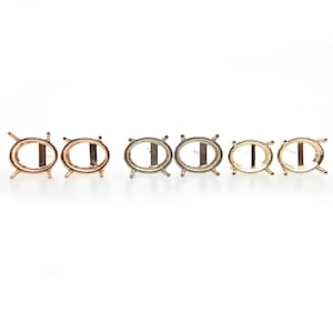 Op de afbeelding: Zes ovale metalen settings voor het maken van sieraden. Twee zijn rosé goud, twee zijn zilver en twee zijn goud.