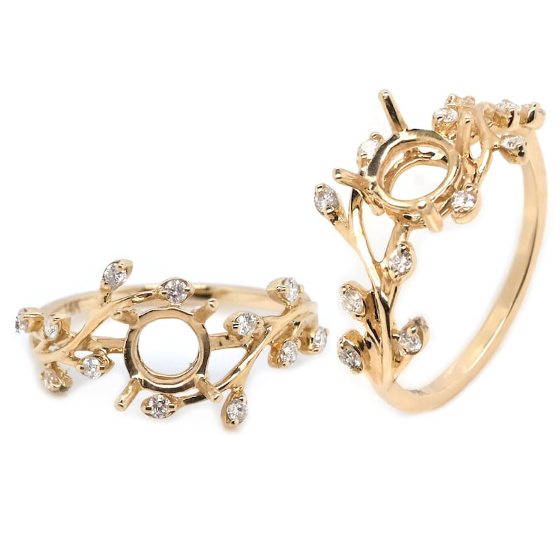 Puede incluir: Un engaste de anillo de oro con un delicado dise&ntilde;o de hojas. El engaste presenta una piedra central redonda y est&aacute; acentuado con peque&ntilde;os diamantes brillantes.