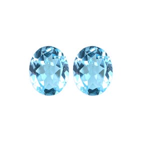 May include: Two round, faceted, light blue gemstones. The gemstones are set in a bezel setting and have a brilliant cut.