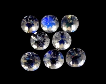May include: Eight round, faceted gemstones with a rainbow sheen are displayed against a black background. The gems are clear with internal color flashes, reflecting light. The arrangement is scattered, showcasing the gems' brilliance.