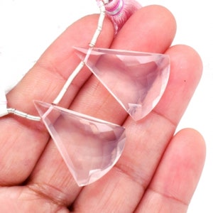 Könnte beinhalten: Zwei klare, facettierte, rosafarbene Quarz-Dreieck-Anhängerperlen mit silbernen Sprungringen. Die Perlen sind etwa 2,5 cm lang.