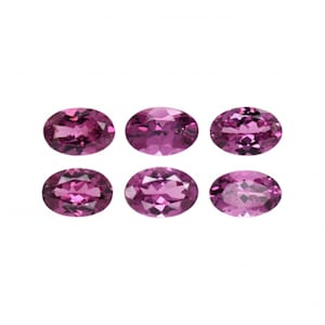 Op de afbeelding: Zes ovale edelstenen, elk in een levendige roze tint, zijn gerangschikt in twee rijen van drie. De edelstenen zijn glad en gepolijst en reflecteren licht.