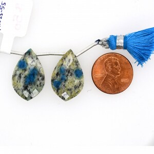 Può includere: Due perle di cianite a forma di goccia, blu e verdi, con un filo d'argento infilato. Un penny americano è incluso per il confronto delle dimensioni.