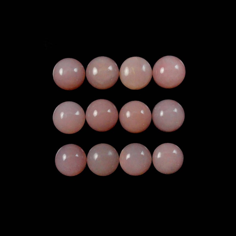 K&ouml;nnte beinhalten: Zw&ouml;lf runde, blassrosa Opal-Cabochons, angeordnet in drei Reihen zu vier. Die Cabochons sind glatt und poliert.