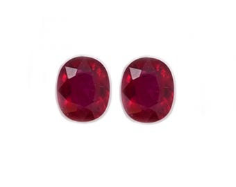 May include: Two oval-shaped ruby gemstones, each with a deep red color and a faceted cut.