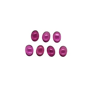 Puede incluir: Ocho piedras preciosas ovaladas de color rosa. Las piedras preciosas son lisas y pulidas.