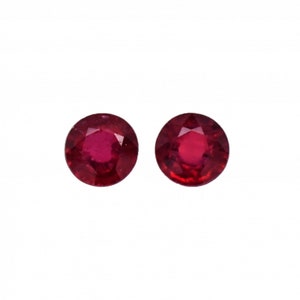 May include: Two round, red gemstones with a faceted cut.