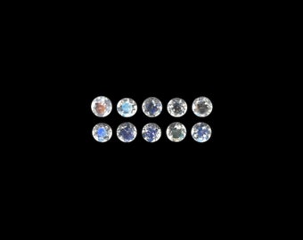 May include: Twelve round, iridescent gemstones arranged in two rows of six. The gemstones are clear with a blue and white iridescent sheen.