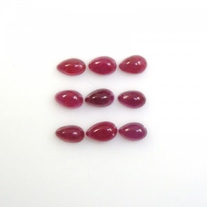 May include: Nine red gemstone cabochons in an oval shape, arranged in three rows of three. The gemstones are smooth and polished.