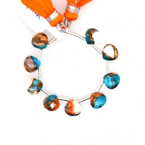 May include: A strand of turquoise, copper, and white gemstone beads in a heart shape. The beads are strung on a silver wire and are accented with orange tassels.