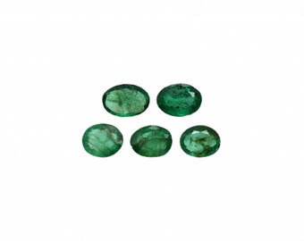 May include: Six oval-shaped emerald green gemstones. The gemstones are smooth and polished.