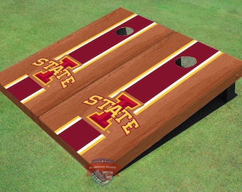 May include: A set of two wooden cornhole boards with a red, white, and gold striped design. The boards feature the Iowa State University logo with the text "STATE" and the letter "I" in a large font.