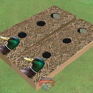May include: Two wooden cornhole boards with a camouflage pattern and a duck image. The boards have three holes each.