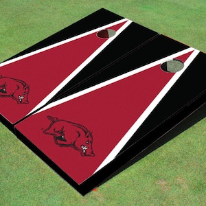 May include: A set of two black and red cornhole boards with white stripes and a red Razorback mascot logo.