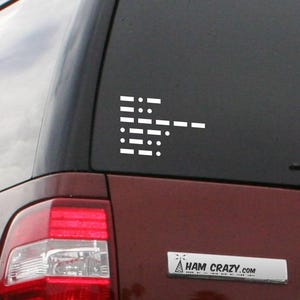 May include: A white Morse code decal on a car window, made up of dots and dashes. The message is likely a word or phrase. The vehicle is a maroon SUV. The website address "HAM CRAZY.com" is visible on a small silver plate.