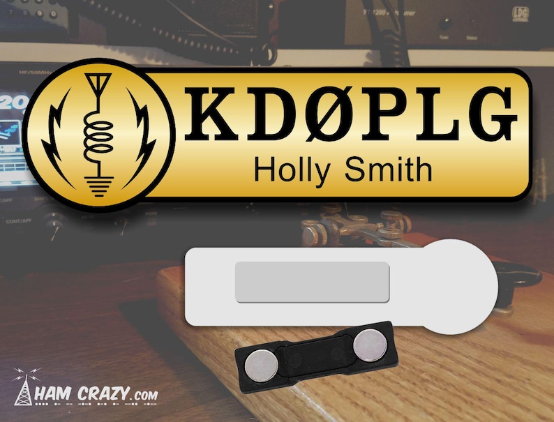May include: A gold name tag with the call sign "KD&Oslash;PLG" and the name "Holly Smith" printed in black text. The tag is attached to a white magnetic name tag holder with a black magnetic clasp.