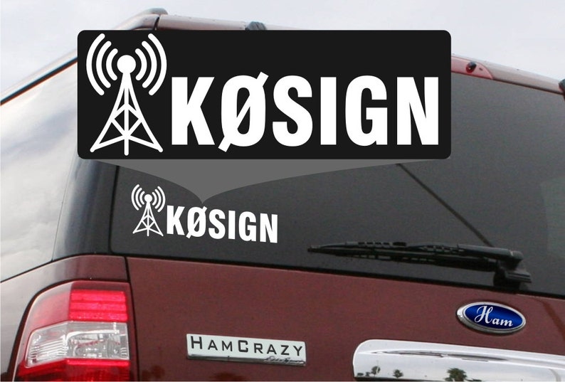 May include: A black car with a white sticker on the back window. The sticker has a white antenna tower symbol and the text "K&Oslash;SIGN".
