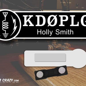 May include: Black and white name tag with the call sign "KD&Oslash;PLG" and the name "Holly Smith" printed on it. The name tag is attached to a white magnetic name tag holder.