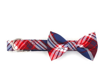 May include: A red, white, and blue plaid bow tie attached to a matching patterned collar with a silver buckle.