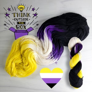 May include: Three skeins of yarn in yellow, white, purple and black colours. The yarn is arranged in a heart shape with the colours representing the non-binary pride flag. The text "Think outside the box" is written above the yarn with a lightbulb graphic.