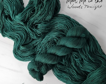 Può includere: Un gomitolo di filo verde scuro, con il testo "Meet Me in the Woods Tonight" scritto in bianco sopra.