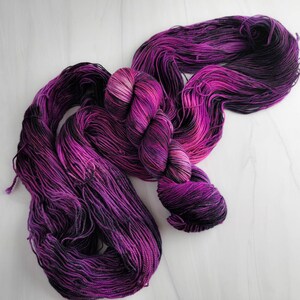 May include: A skein of purple and black yarn with a gradient effect. The yarn is soft and fluffy, and it would be perfect for knitting or crocheting.