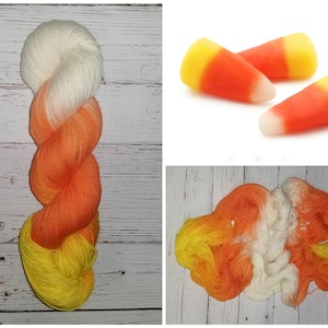 May include: A skein of yarn with a gradient of white, orange, and yellow colors. The yarn is arranged in a spiral shape. The yarn is similar in color to candy corn.