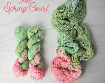 Può includere: Due gomitoli di filato in un degradé di colore verde e rosa. Il filato si chiama "The Spring Court".