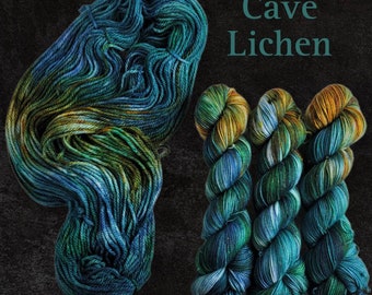 May include: Three skeins of yarn in shades of blue, green, and gold. The yarn is called "Cave Lichen".
